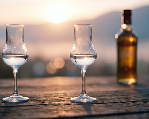 Tulpenglas mit klarem wei�en Grappa auf Holztisch, Roner Brennerei S�dtirol