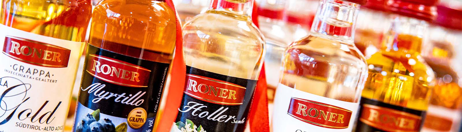 Roner kleine Flaschen nebeneinander Grappa, Myrtillo, Holler mit rotem Band
