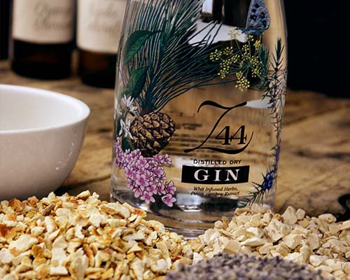 Roner Gin Flaschenauschnitt neben wei�em Porzellan und Ginzutaten