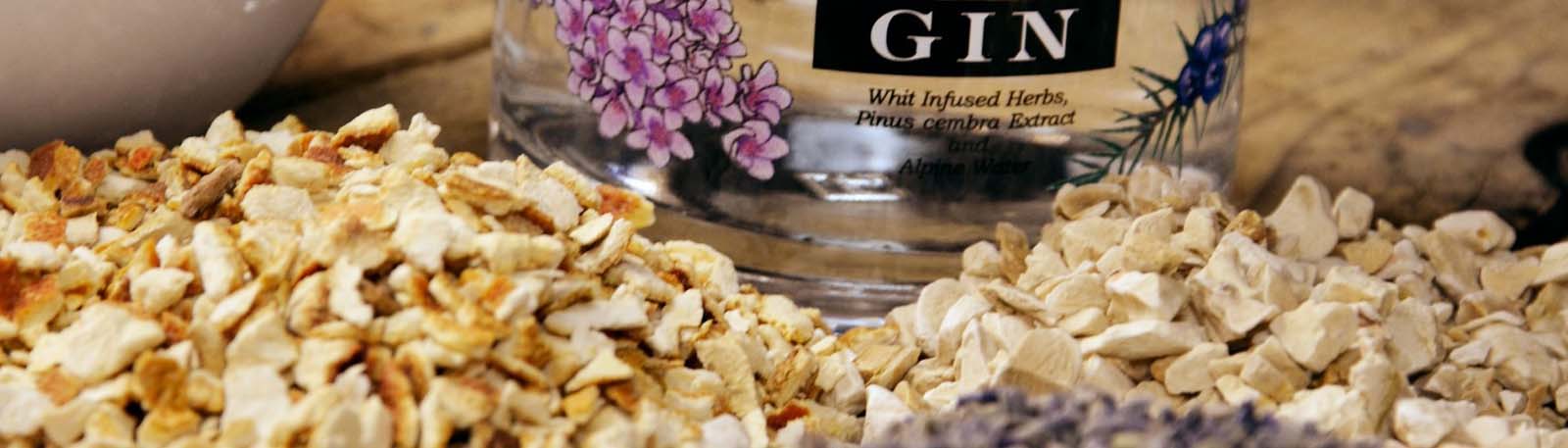 Roner Gin Flaschenauschnitt neben wei�em Porzellan und Ginzutaten
