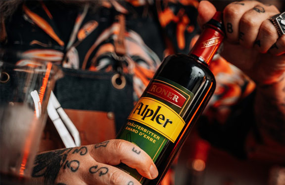 Roner Kr�uterlik�r in Flasche mit H�nden eines coolen Typen der t�towiert ist